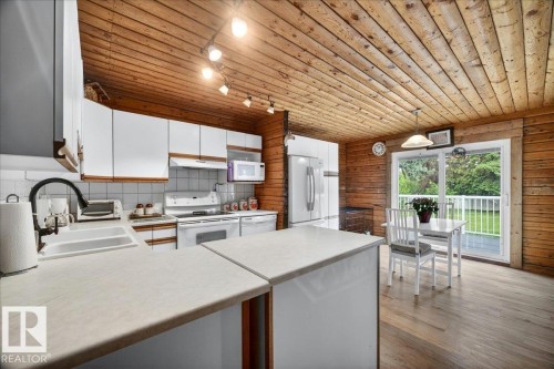 Kitchen featuring wood-finish walls and ceiling, white cabinetry, and light-toned countertops - 140 50047 Rge Rd 244, Rural Leduc County, AB 
