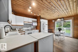 Kitchen featuring wood-finish walls and ceiling, white cabinetry, and light-toned countertops - 