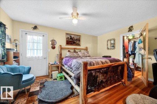 Bedroom featuring wood-finish flooring, a ceiling fan with integrated lighting, and a white paneled door with glass inserts - 140 50047 Rge Rd 244, Rural Leduc County, AB 