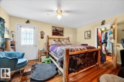 Bedroom featuring wood-finish flooring, a ceiling fan with integrated lighting, and a white paneled door with glass inserts - 