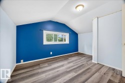 Room featuring wood-finish flooring, a vaulted ceiling, a single window, and a flush mount light fixture - 