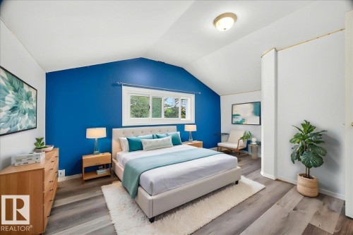 Vaulted ceiling bedroom featuring a vibrant accent wall, expansive window, wood-finish flooring, and a flush-mount ceiling light fixture - 140 50047 Rge Rd 244, Rural Leduc County, AB 