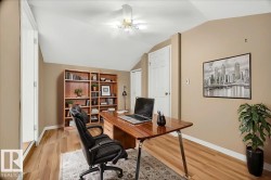 Room featuring an angled ceiling, wood-finish flooring, a built-in wood bookcase, and a white paneled door - 