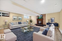 Finished basement area featuring wood-finish flooring, a brick-surround fireplace with a wood mantle, and a drop ceiling with recessed lighting - 