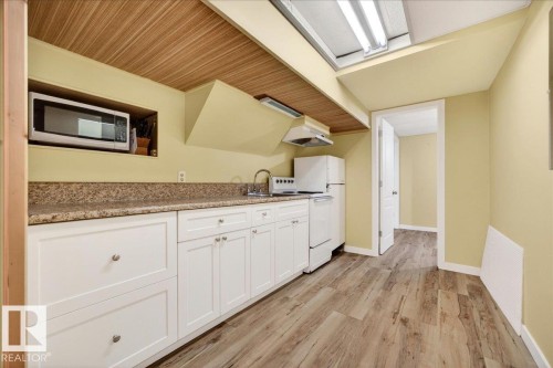 Kitchenette featuring a wood-finish ceiling, light wood-finish flooring, white cabinetry, speckled countertops, and a full-size refrigerator - 140 50047 Rge Rd 244, Rural Leduc County, AB 