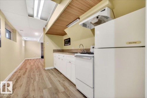 Compact kitchen area featuring white cabinetry, a built-in microwave, a stainless steel sink, and light-toned countertops - 140 50047 Rge Rd 244, Rural Leduc County, AB 