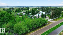 Expansive property featuring lush green landscapes, a substantial main residence, and additional outbuildings - 