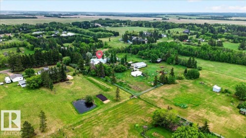 Expansive rural property featuring multiple outbuildings, mature trees, open fields, and a private pond - 140 50047 Rge Rd 244, Rural Leduc County, AB 