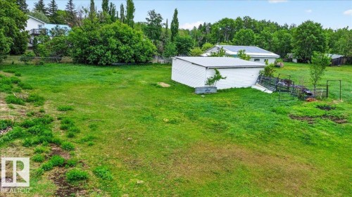 Expansive green space featuring a white outbuilding with a metal roof, surrounded by mature trees - 140 50047 Rge Rd 244, Rural Leduc County, AB 