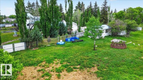Expansive green space featuring mature trees, a chain-link fence, and a distant structure - 140 50047 Rge Rd 244, Rural Leduc County, AB 