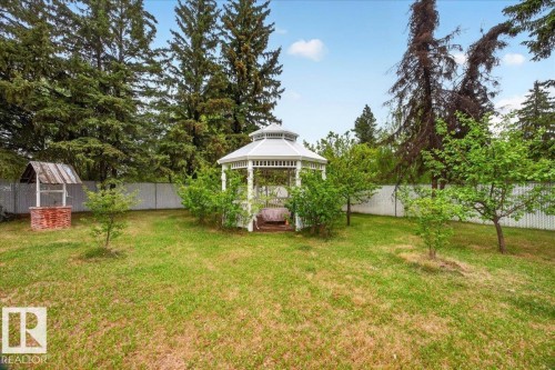 Expansive backyard featuring a white gazebo, a decorative well with a brick base, and mature perimeter trees - 140 50047 Rge Rd 244, Rural Leduc County, AB 