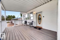 Covered front porch featuring wood-finish decking, white railings, and a white siding exterior - 