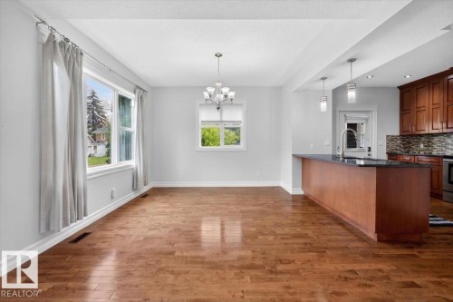 Spacious interior featuring wood-finish flooring, white walls, and abundant natural light from multiple windows - 10958 88 Avenue, Edmonton, AB 