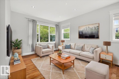 Spacious living area featuring wood-finish flooring, recessed lighting, and multiple windows - 10958 88 Avenue, Edmonton, AB 