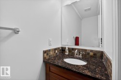 Vanity area featuring a dark stone countertop with an integrated oval sink, a mosaic tile backsplash, and a wood-finish vanity cabinet - 
