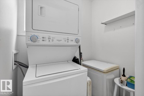 Dedicated laundry area featuring a stacked washer and dryer, a window, and a wall-mounted shelving unit - 10958 88 Avenue, Edmonton, AB 
