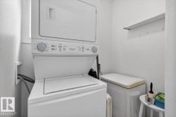 Dedicated laundry area featuring a stacked washer and dryer, a window, and a wall-mounted shelving unit - 