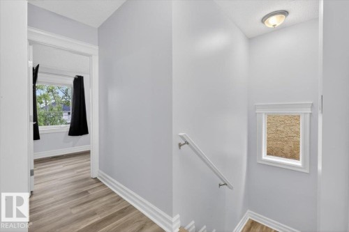 Light gray walls with white trim, wood-finish flooring, white window frames, and a flush mount ceiling light - 10958 88 Avenue, Edmonton, AB 