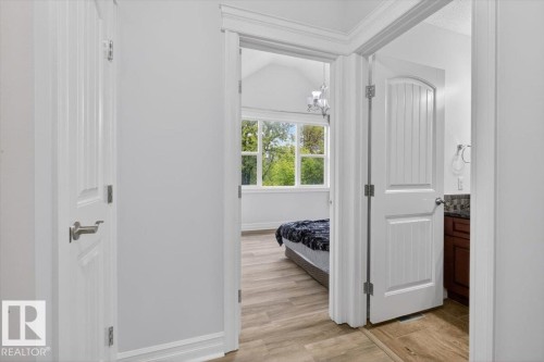 Hallway featuring white trim and doors, wood-finish flooring, and a recessed vent - 10958 88 Avenue, Edmonton, AB 