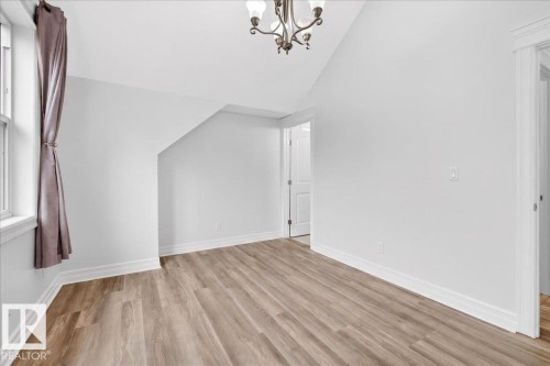 Room featuring wood-finish flooring, white baseboards, and a window with trim - 10958 88 Avenue, Edmonton, AB 