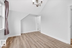 Room featuring wood-finish flooring, white baseboards, and a window with trim - 
