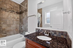 Bathroom featuring a tub/shower combination with large format tiled surround and decorative accent band - 