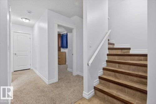 Staircase featuring tile treads with wood-finish nosing and a white handrail - 10958 88 Avenue, Edmonton, AB 