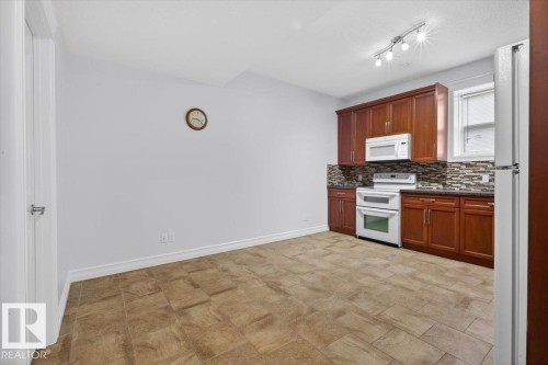 Kitchen area featuring wood cabinetry, white appliances, mosaic tile backsplash, and track lighting - 10958 88 Avenue, Edmonton, AB 