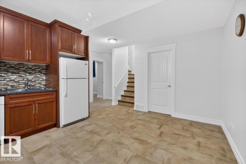 Kitchenette featuring wood cabinetry, integrated sink, and a mosaic tile backsplash - 10958 88 Avenue, Edmonton, AB 