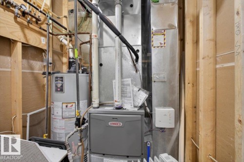 Utility room featuring a water heater, furnace, and exposed wood framing - 10958 88 Avenue, Edmonton, AB 