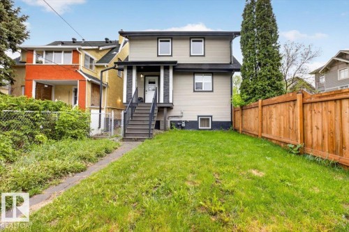 Rear exterior featuring light-colored siding with dark trim accents - 10958 88 Avenue, Edmonton, AB 