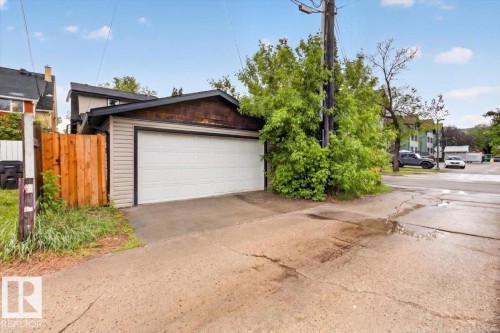 Detached garage featuring a white overhead door, horizontal siding, and wood-shingle accents - 10958 88 Avenue, Edmonton, AB 