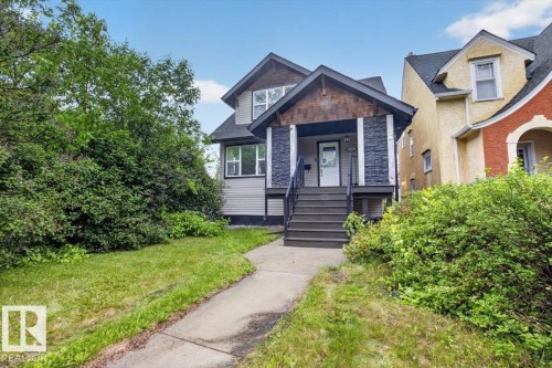 Two-story residence featuring a dark gray shingle roof, light gray horizontal siding, and dark gray stone veneer accents - 10958 88 Avenue, Edmonton, AB 