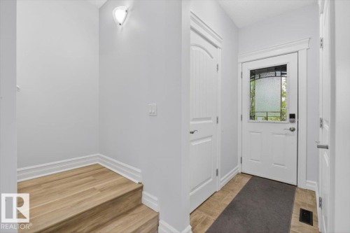 Entryway featuring a white door with decorative glass inserts, ceramic tile flooring, and a built-in coat closet - 10958 88 Avenue, Edmonton, AB 