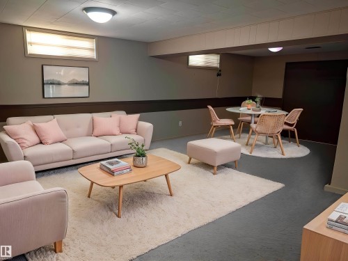 Finished lower level featuring a drop ceiling, wall-mounted light fixtures, window treatments, and a dark brown accent wall - 9443 75 Street, Edmonton, AB 