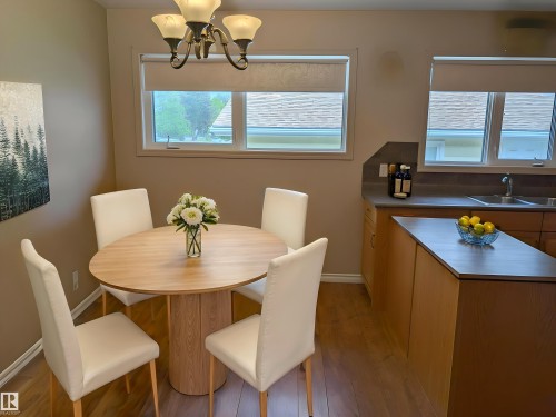 Dining area featuring wood-finish flooring and a contemporary chandelier - 9443 75 Street, Edmonton, AB 