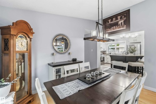Dining area featuring wood-finish flooring and a contemporary chandelier - 11431 144 Avenue, Edmonton, AB 