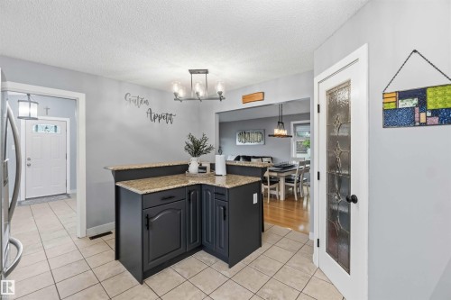 Kitchen featuring dark cabinetry, granite countertops, and tile flooring - 11431 144 Avenue, Edmonton, AB 
