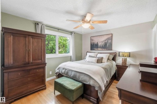 Hardwood-style flooring extends throughout this room, featuring a large window with white trim - 11431 144 Avenue, Edmonton, AB 