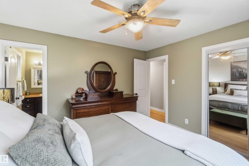 Bedroom featuring neutral wall color, overhead ceiling fan with lighting, wood-finish flooring, and a mirrored closet - 11431 144 Avenue, Edmonton, AB 