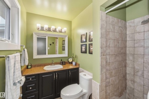 Bathroom featuring a dark wood-finish vanity with an undermount sink, a warm-toned countertop, and a framed mirror with overhead lighting - 11431 144 Avenue, Edmonton, AB 