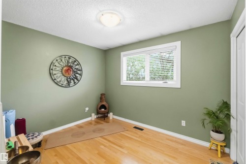 Bright room featuring light wood-finish flooring, a contemporary ceiling light fixture, and a white-framed window with blinds - 11431 144 Avenue, Edmonton, AB 