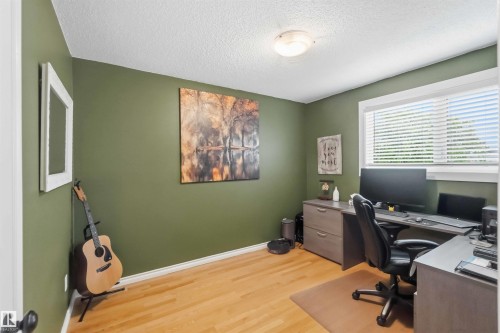 Spacious interior room featuring wood-finish flooring, a window with blinds, and a built-in flush-mount ceiling light - 11431 144 Avenue, Edmonton, AB 