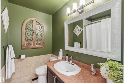Bathroom featuring a vanity with an integrated sink, a large framed mirror, and a wall-mounted light fixture - 11431 144 Avenue, Edmonton, AB 