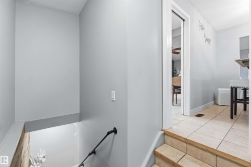 Stairwell featuring a dark metal handrail and light gray walls - 11431 144 Avenue, Edmonton, AB 
