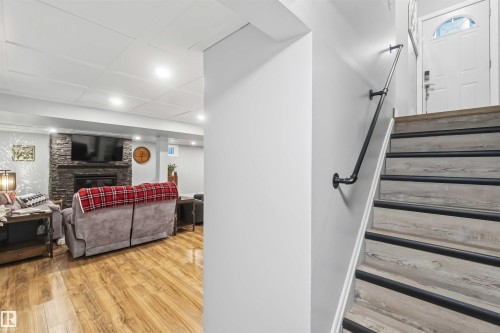 Staircase with light wood-finish treads, black non-slip strips, and a black pipe-style handrail - 11431 144 Avenue, Edmonton, AB 
