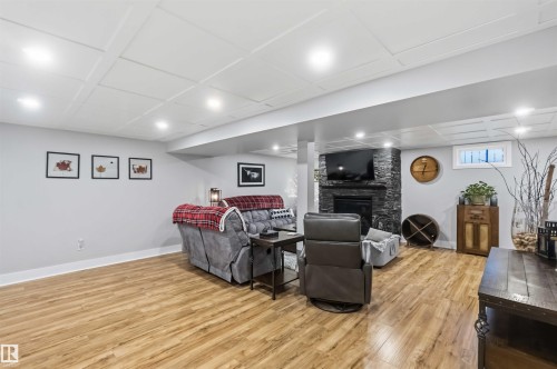 Spacious living area featuring wood-finish flooring and a stone-clad fireplace - 11431 144 Avenue, Edmonton, AB 