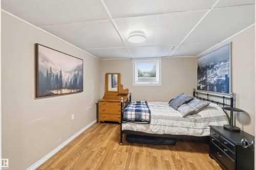 Bedroom featuring wood-finish flooring, neutral wall paint, white trim, and a drop ceiling with recessed lighting - 11431 144 Avenue, Edmonton, AB 