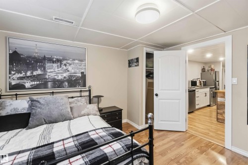 Bedroom featuring light beige walls, wood-finish flooring, and a white ceiling with paneling and a flush-mount light fixture - 11431 144 Avenue, Edmonton, AB 