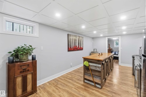 Reclaimed wood-finish island with a natural wood countertop, wood-finish flooring, recessed lighting, and a drop ceiling - 11431 144 Avenue, Edmonton, AB 